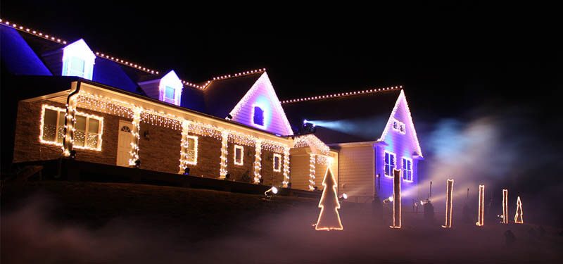 House outlined in lights with blue and violet washes and fog