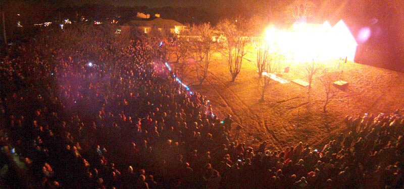 Aerial view of a huge nighttime crowd facing the glowing show